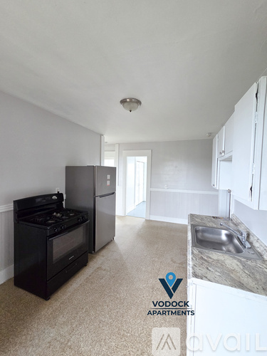 A Vodock Apartments kitchen with a black stove and white cabinets.