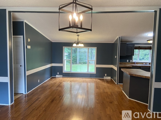 A room with wooden floors and a chandelier hanging from the ceiling.