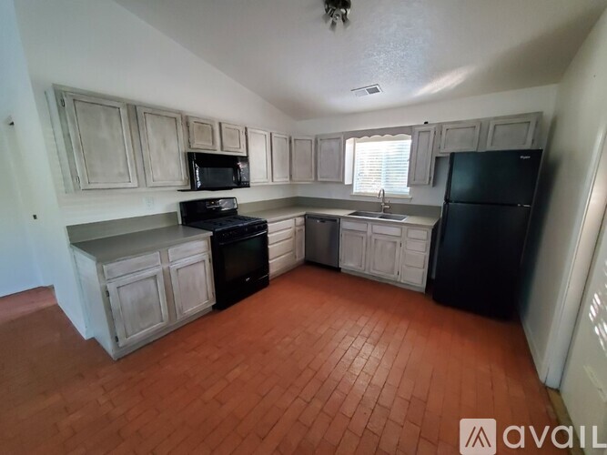 A kitchen with black appliances and wooden floors.