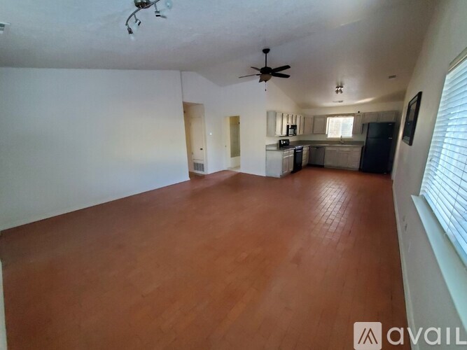 A spacious room with wooden flooring and a ceiling fan.