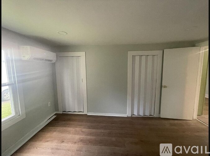 A room with a window, a door, and a wall-mounted air conditioner.