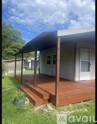 A small white house with a wooden deck and a covered porch.