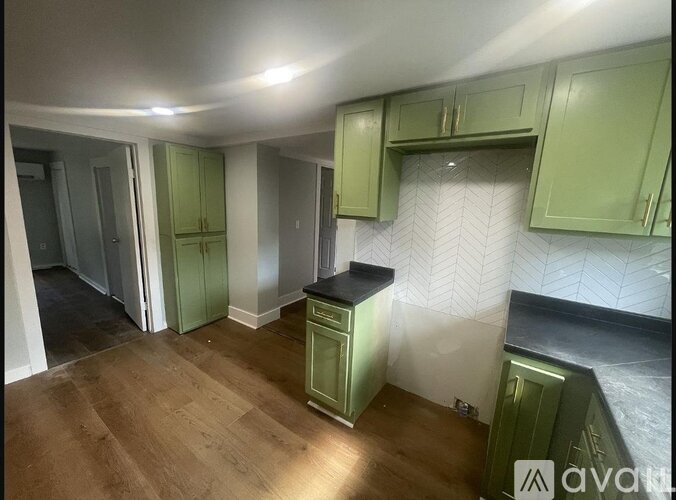 A kitchen with green cabinets and a wooden floor.
