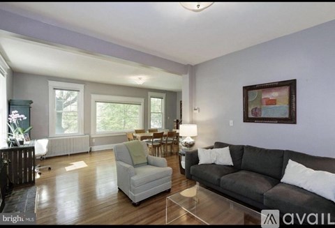 A living room with a grey couch and a glass table.
