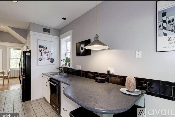 A kitchen with a black fridge and a black and white tiled backsplash.