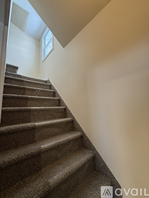 A staircase with a carpeted runner and a window above it.