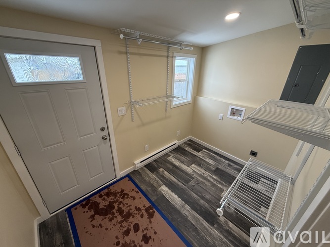 A room with a white door and a window with a metal railing.