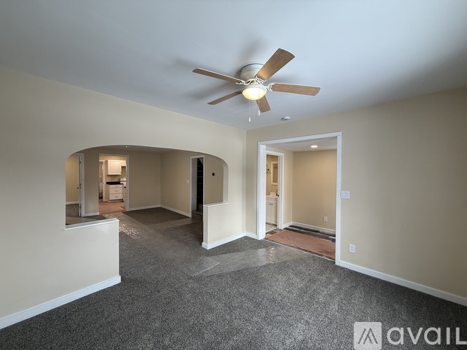 A spacious room with a ceiling fan and carpeted floor.