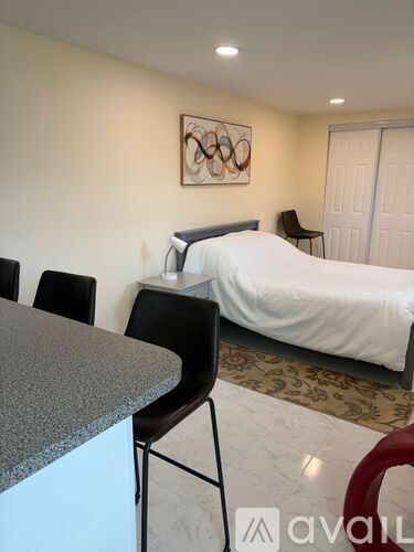 A bedroom with a bed, chair, and a painting on the wall.