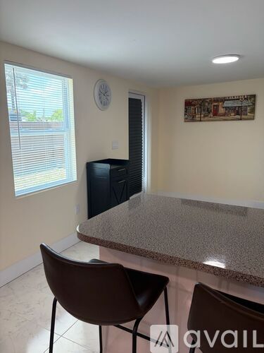 A kitchen with granite countertops and two brown chairs.