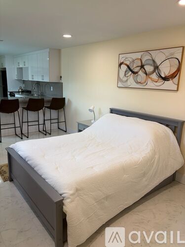 A bedroom with a large bed and a painting on the wall.