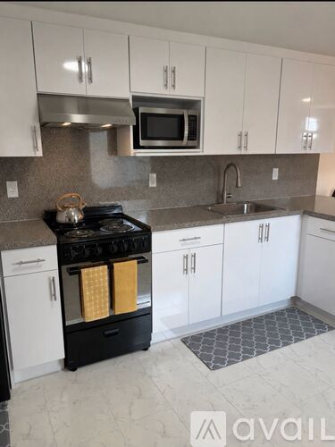 A kitchen with white cabinets and a black stove top oven.