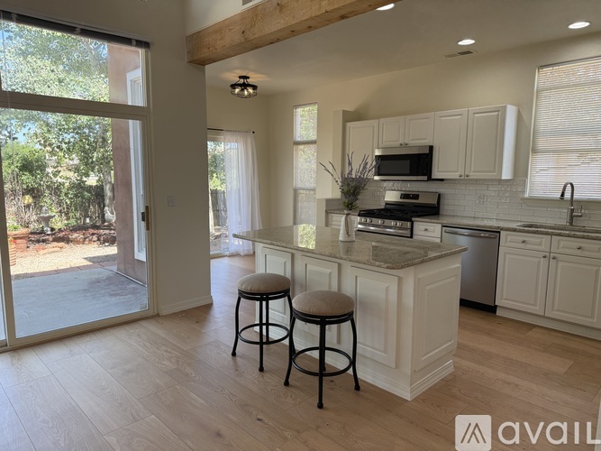 A kitchen with white cabinets and a bar stool.