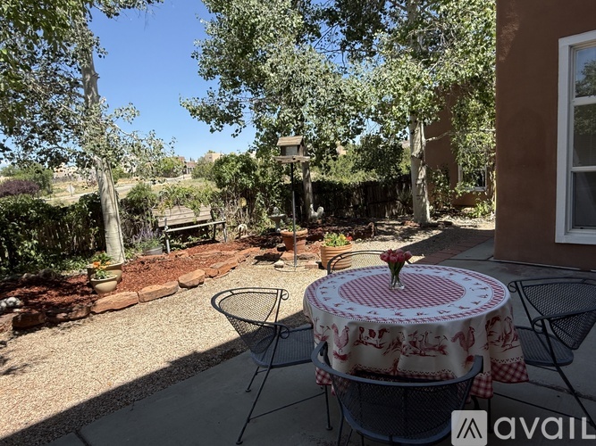 A patio with a table and chairs surrounded by trees.