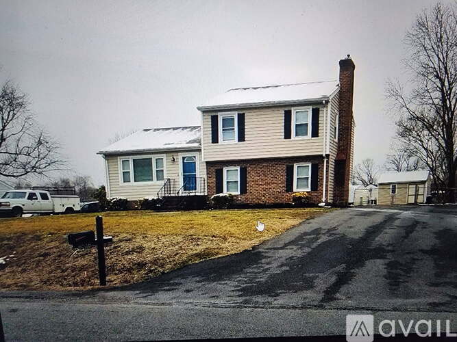 A house with a white picket fence and a driveway in front.
