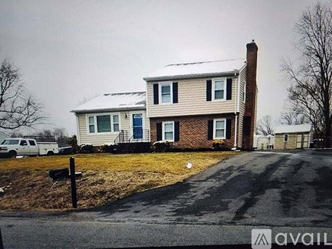 A house with a white picket fence and a driveway in front.