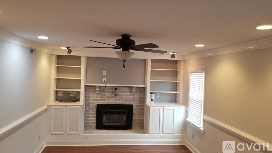 A living room with a fireplace and a ceiling fan.