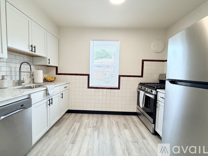 A kitchen with white cabinets and a stainless steel refrigerator.