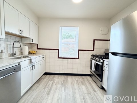 A kitchen with white cabinets and a stainless steel refrigerator.