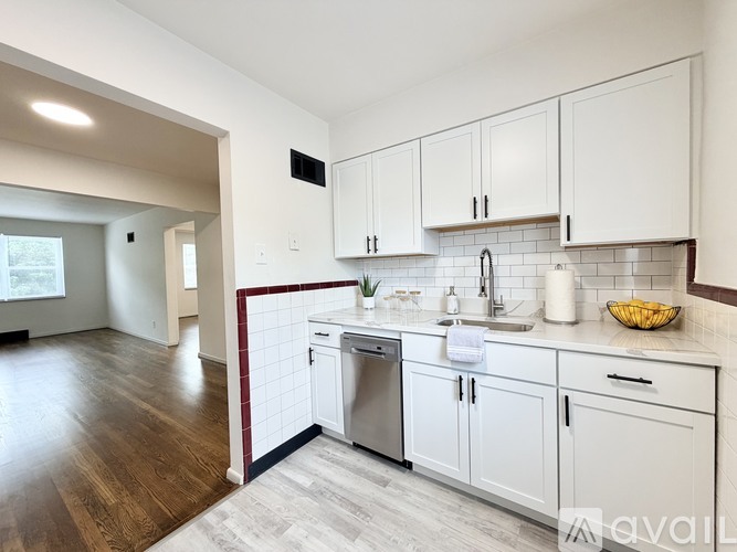A kitchen with white cabinets and a wooden floor.