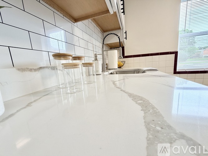 A kitchen with white tiles and a marble countertop.