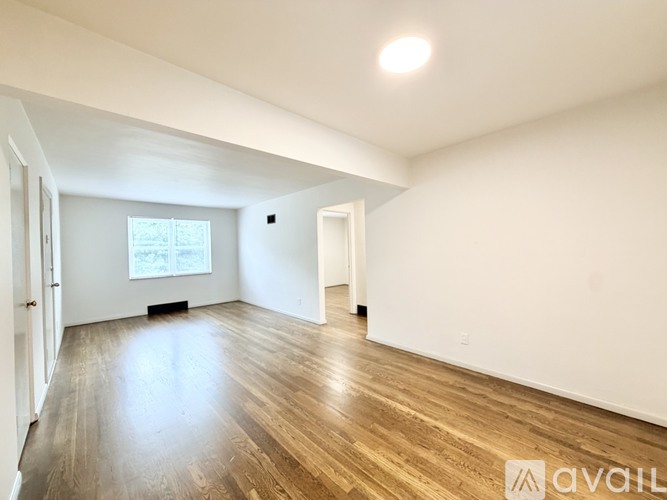 A spacious room with wooden flooring and white walls.