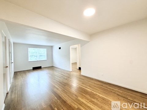 A spacious room with wooden flooring and white walls.