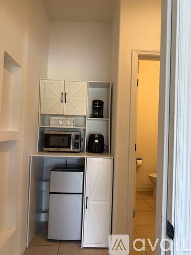 A kitchen area with a microwave, toaster, and coffee maker on a cabinet.