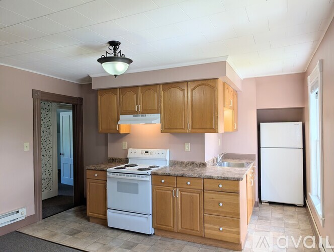 A kitchen with wooden cabinets and a white stove top oven.