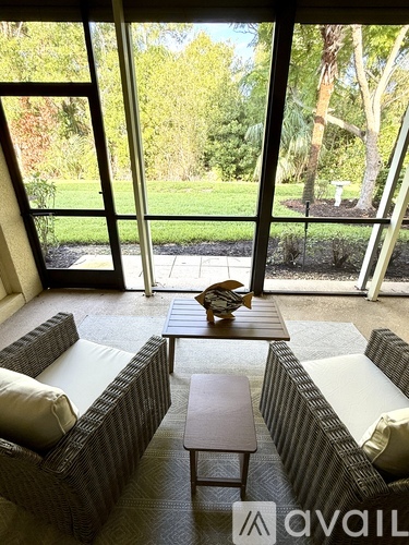 A living room with a couch, table, and a window overlooking a garden.