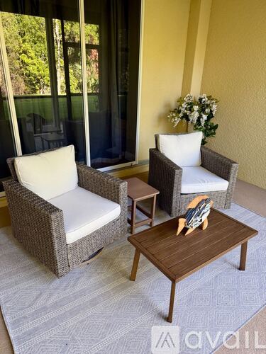 A patio with two chairs and a table with a vase of flowers on it.