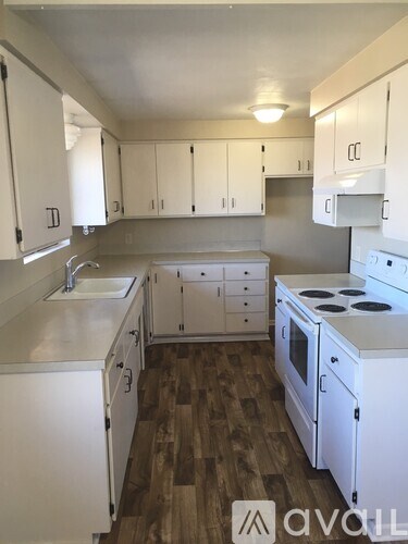 A kitchen with white cabinets and a wooden floor.