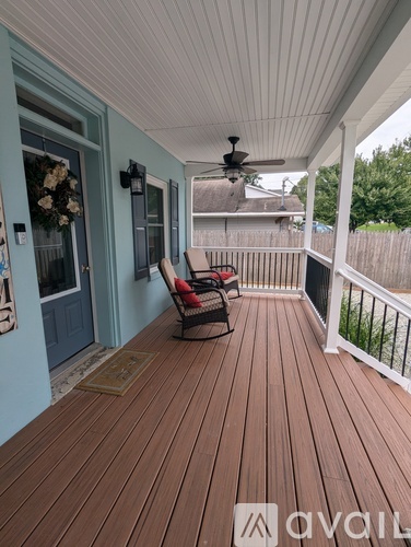 A wooden deck with a ceiling fan and a chair.
