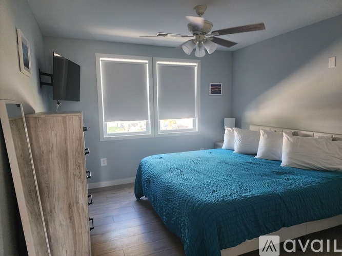 A bedroom with a bed covered in a blue blanket and a ceiling fan.