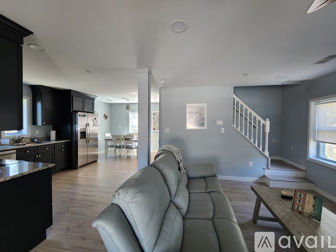 A modern living room with a grey sofa and a kitchen in the background.