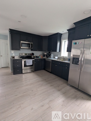 A kitchen with black cabinets and a wooden floor.