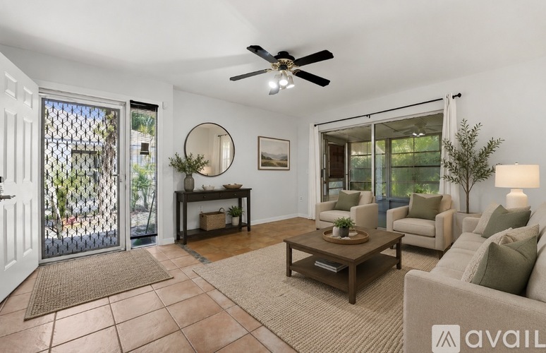 A living room with a ceiling fan and a table with a plant on it.
