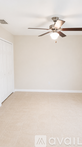 A room with a ceiling fan and beige walls.