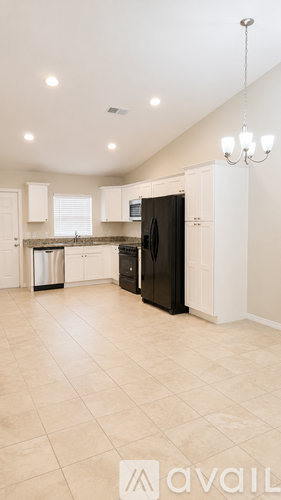 A kitchen with a black refrigerator and white cabinets.