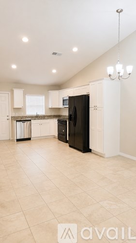 A kitchen with a black refrigerator and white cabinets.