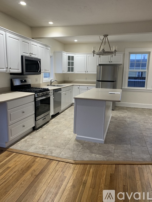 A kitchen with white cabinets and a wooden floor.