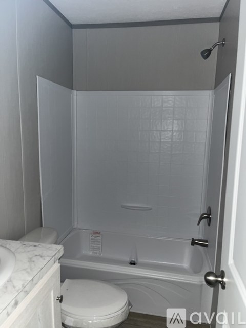 A white toilet sits next to a walk-in shower.