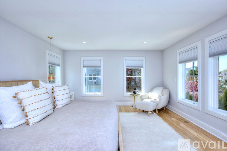 A bedroom with a large bed and a white chair.