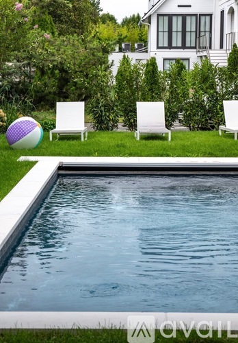 A pool with a white fence and a white house in the background.