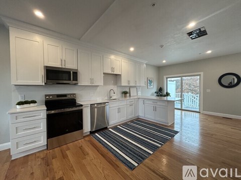 A kitchen with white cabinets and a wooden floor.