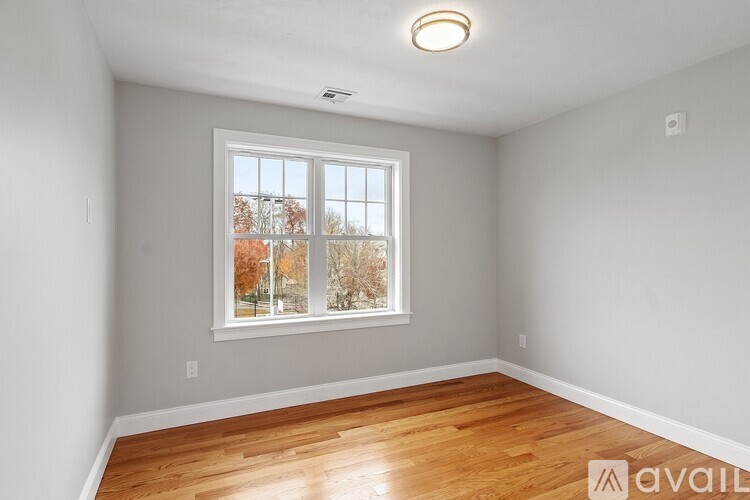 A room with a window showing a view of trees with autumn leaves.