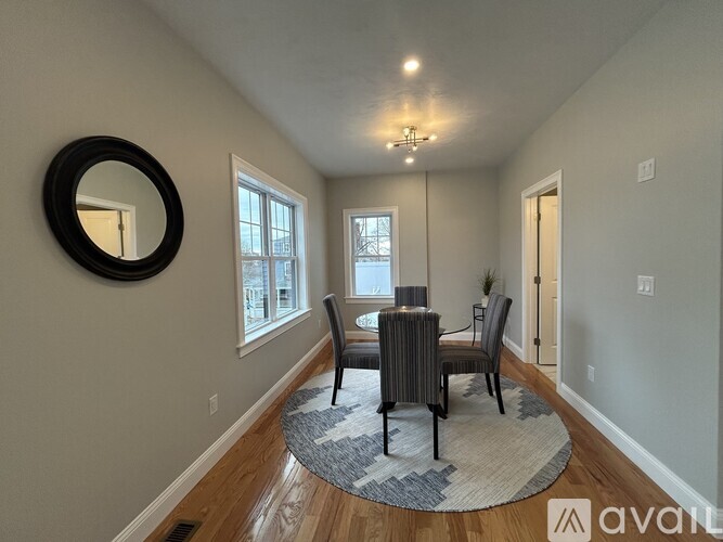 A dining room with a round mirror on the wall.