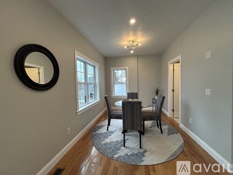 A dining room with a round mirror on the wall.