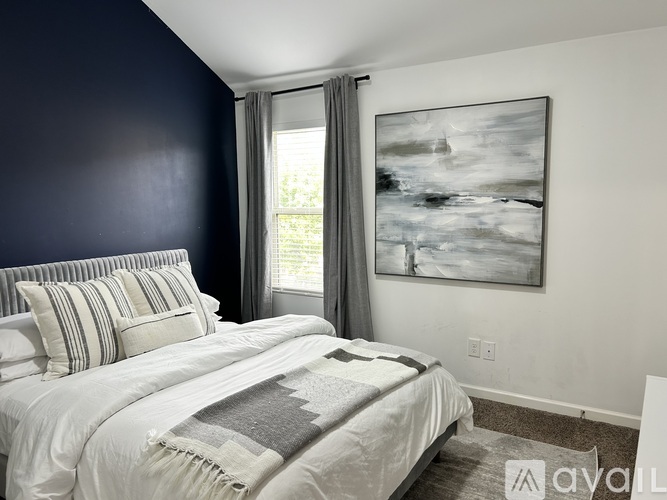 A bedroom with a large bed and a painting on the wall.