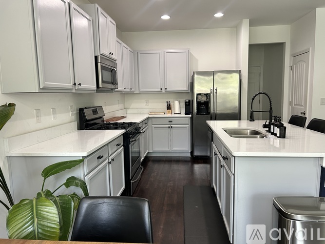 A kitchen with white cabinets and a black chair.